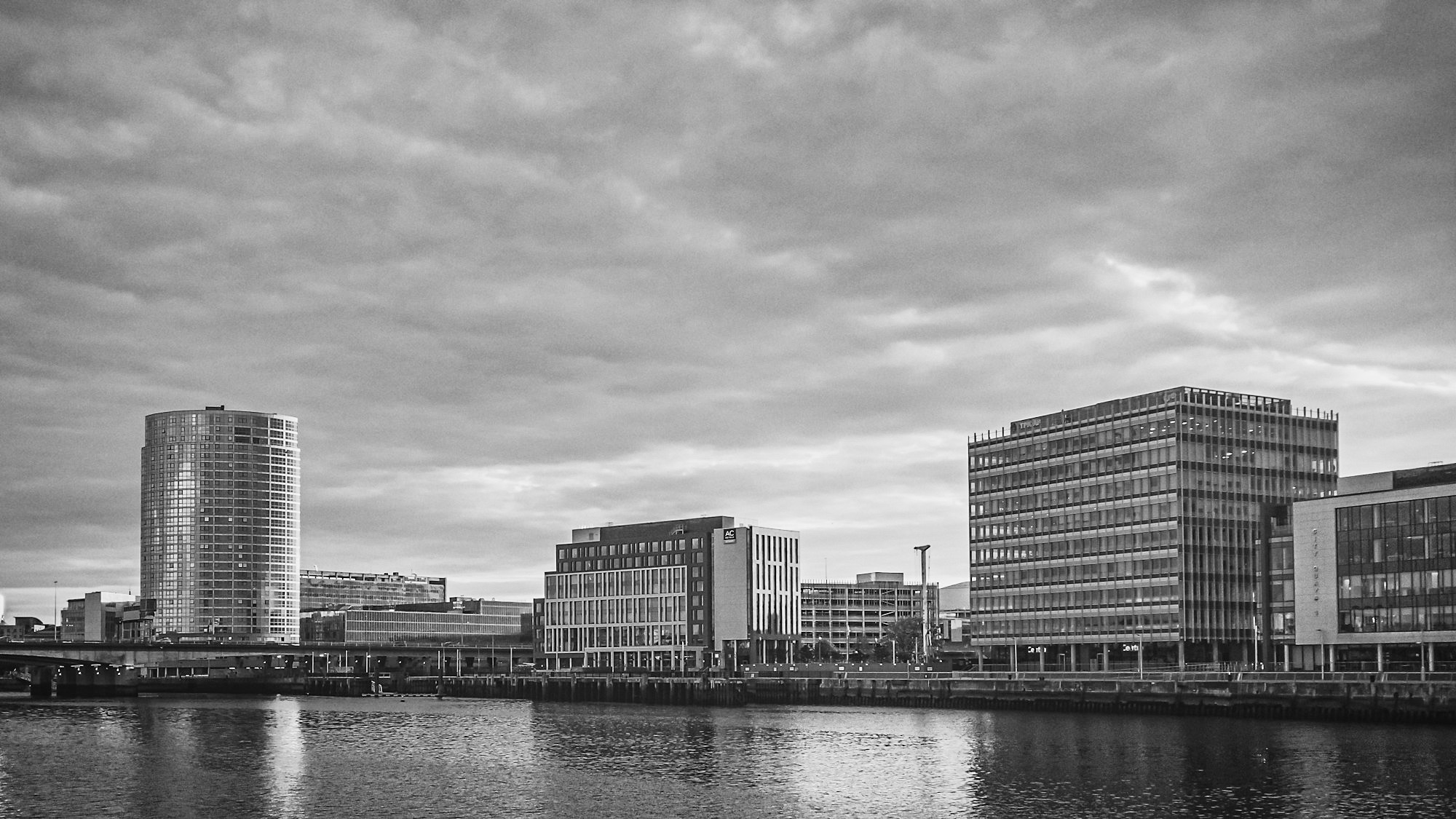 Belfast city centre across the Lagan from Titanic Quarter, in black and white under a heavy sky